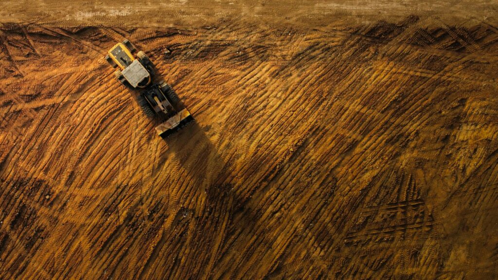 Top-down view of a bulldozer moving earth on a large construction site.
